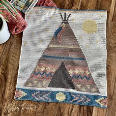 a native american teepeel rug next to a cup of coffee on a wooden table