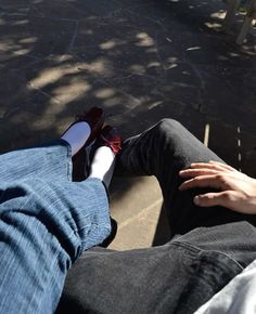 two people sitting on the ground with their feet up and one person wearing red shoes