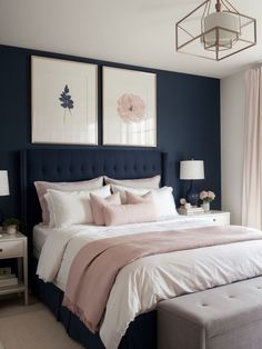 a bedroom with blue walls, white bedding and two pictures hanging above the bed