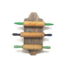 three wooden pegs are attached to the back of a wall mounted rack with green handles