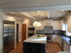 a large kitchen with an island in the middle and stainless steel appliances on both sides