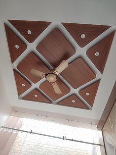 a ceiling fan mounted to the side of a wooden paneled ceiling in a room