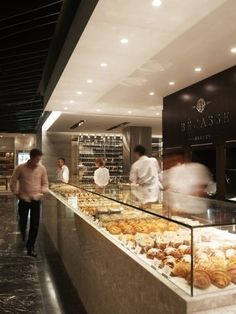 people are standing in front of a bakery counter