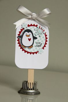 a penguin with a bow on top of a small popsicle shaped like a snowman