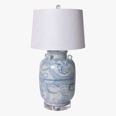 a blue and white ceramic lamp with a white shade on the top, against a white background