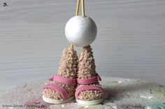 a pair of baby shoes hanging from a hook with a ball attached to the top