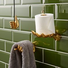 two rolls of toilet paper hanging from the wall next to a towel rack with gold handles