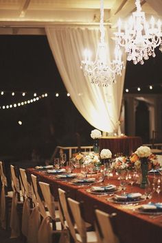 a long table is set with place settings and flowers