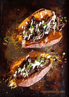 two stuffed sweet potatoes topped with toppings on a baking sheet, ready to be eaten