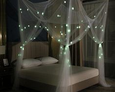 a bed with white netting and green lights on it