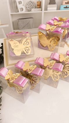 there are many boxes with pink and gold decorations on the top one has a butterfly in it