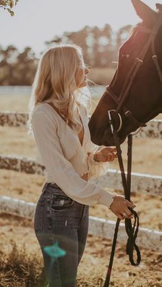 a beautiful blonde woman standing next to a horse