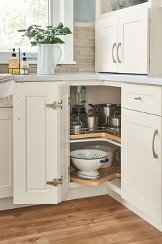 an open cabinet in a kitchen with pots and pans