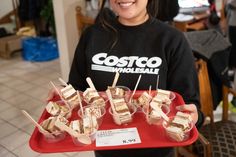 a woman holding a tray with desserts on it