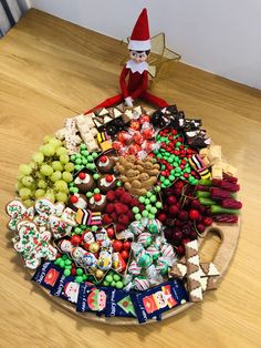 an elf is sitting on top of a platter full of sweets and candies