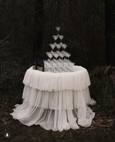 a table with a cake on it in the middle of some trees and grass at night