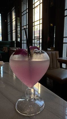 a pink drink sitting on top of a white counter next to a window in a restaurant