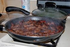 a skillet filled with meat cooking on top of a stove next to an oven