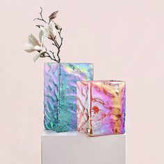 two vases sitting on top of each other with flowers in the middle and one is made out of marble