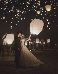 a bride and groom are surrounded by floating lanterns