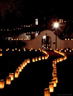 many lit up paper lanterns are in the dark, with one person standing at the end