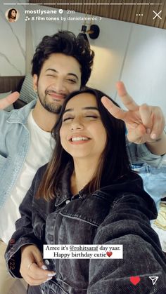 two people are smiling and making the peace sign with their hands in front of them