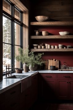 a kitchen with red walls and wooden shelves filled with pots, pans and bowls