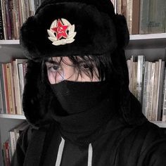 a person wearing a black hat with a red star on it and a scarf around their neck