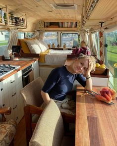 a woman sitting at a kitchen table in a camper with lots of furniture and decor