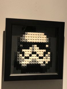 a black frame with white legos in it on the wall next to a gray wall