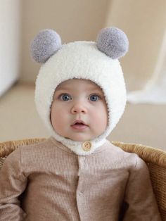 a baby wearing a bear hat sitting in a basket