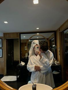 a man taking a selfie in front of a mirror with his robe draped around him