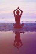 a person sitting in the water with their hands up to their head while doing yoga