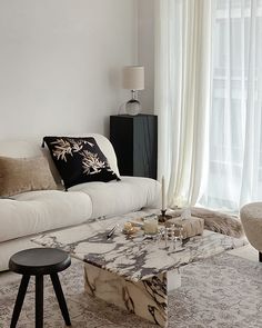 a living room filled with furniture and a large window covered in white draping