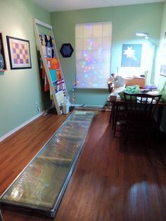 a room with hard wood flooring and a long glass table on the ground in front of it