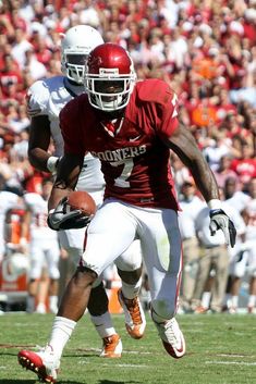 a football player running with the ball in his hand and people watching from the stands