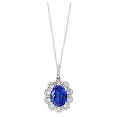 A simple floral motif pendant necklace showcasing a vibrant 2.45-carat oval cut tanzanite, surrounded by 0.74 carats of 62 accent round diamonds. Made in 18 karats white gold. Style available in different price ranges. Prices are based on your selection of the 4C’s (Carat, Color, Clarity, Cut). Please contact us for more information. White Gold Tanzanite Oval Necklaces, Classic Oval Tanzanite Necklace, Classic Oval Tanzanite Necklaces, Elegant Oval Tanzanite Necklaces, Oval Tanzanite Necklace Fine Jewelry, Flower Pendant Necklace, Diamond Halo, Flower Pendant, Gold Style