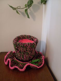 a crocheted hat sitting on top of a wooden table next to a plant