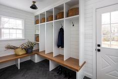 a mud room with white walls and wooden shelves