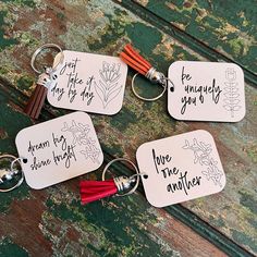 four keychains with different sayings on them sitting on a wooden table next to each other