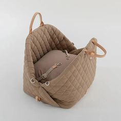 a baby seat in the shape of a quilted bag with handles and straps on it