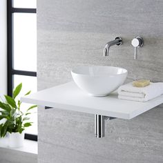 a white bowl sink sitting on top of a counter next to a potted plant