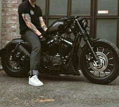 a man sitting on top of a motorcycle next to a brick wall and garage door