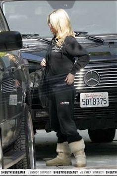 a blonde woman standing next to a black car