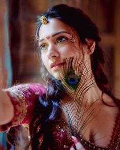 a beautiful woman with peacock feathers on her head and body, posing for the camera