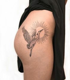 a woman's thigh with a tattoo of a bird flying in the sky above her