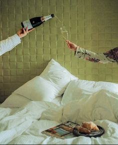 two women toasting with wine glasses on a bed