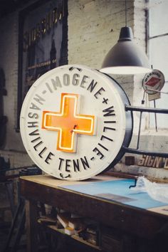 an orange and white sign on top of a table next to a light hanging from the ceiling