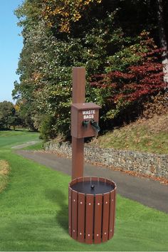 a wooden trash can sitting in the middle of a lush green park