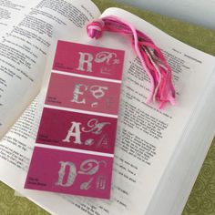 an open book with pink and red stickers on it next to a tassell